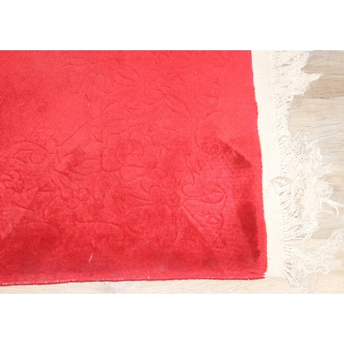 210 - A red ground rug with floral decoration, one of two in the sale, 209cm x 94cm