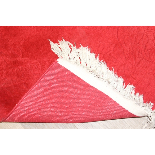 210 - A red ground rug with floral decoration, one of two in the sale, 209cm x 94cm