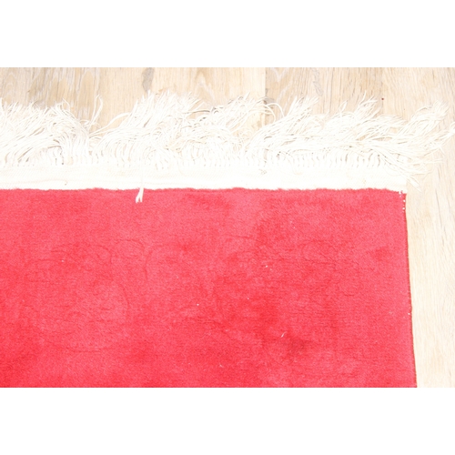 210A - A red ground rug with floral decoration, one of two in the sale, 209cm x 94cm