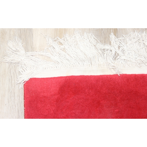 210A - A red ground rug with floral decoration, one of two in the sale, 209cm x 94cm