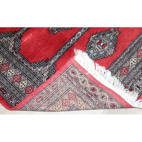 214 - A red ground Uzbek style Bukhara rug, made in Pakistan, 138cm x 94cm