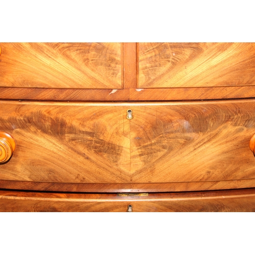 181 - A Victorian flame mahogany bow fronted two over three chest of drawers with bun handles and turned f... 