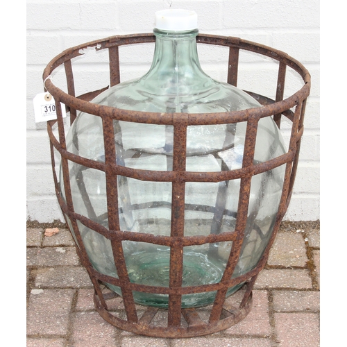 313 - A large vintage glass carboy in iron basket, 52cm in diameter x 62cm tall