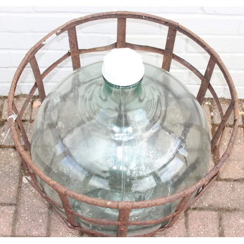 313 - A large vintage glass carboy in iron basket, 52cm in diameter x 62cm tall