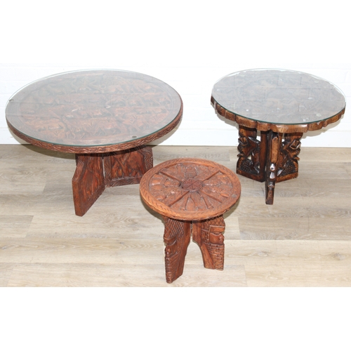 66 - Three African carved hardwood folding tables, the tops carved with elephants, rhinos, giraffes etc, ... 