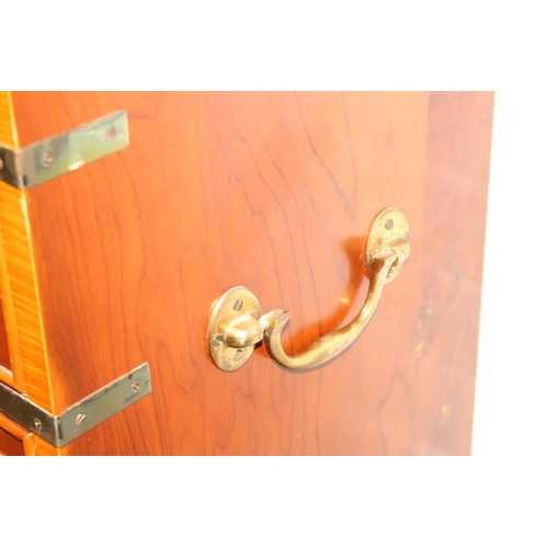 19 - A modern yew wood effect campaign chest with seven drawers and recessed brass campaign style handles... 