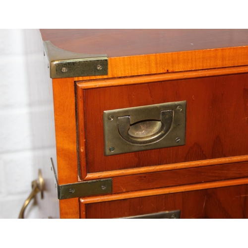 19 - A modern yew wood effect campaign chest with seven drawers and recessed brass campaign style handles... 