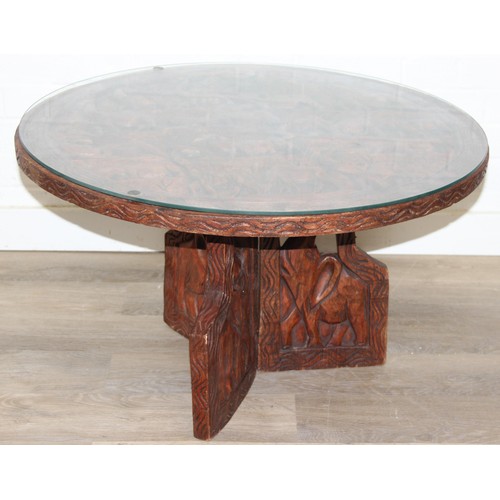 66 - Three African carved hardwood folding tables, the tops carved with elephants, rhinos, giraffes etc, ... 
