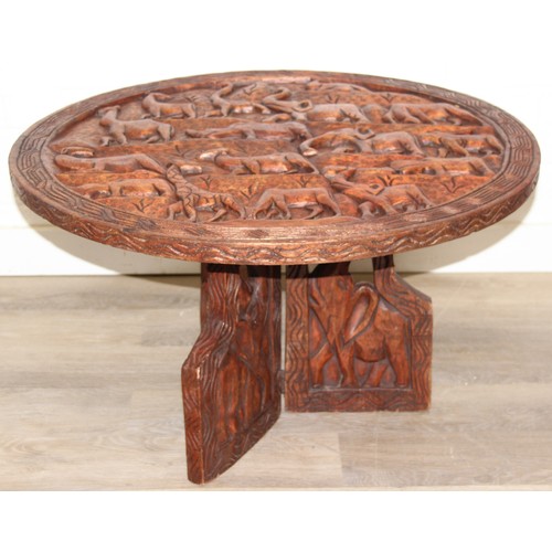 66 - Three African carved hardwood folding tables, the tops carved with elephants, rhinos, giraffes etc, ... 