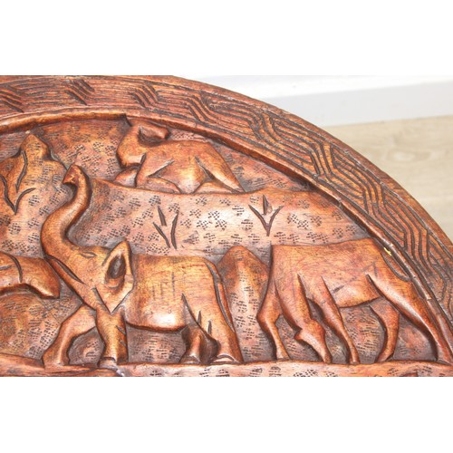 66 - Three African carved hardwood folding tables, the tops carved with elephants, rhinos, giraffes etc, ... 