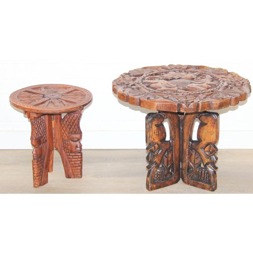 66 - Three African carved hardwood folding tables, the tops carved with elephants, rhinos, giraffes etc, ... 