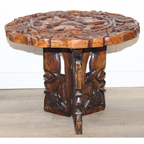 66 - Three African carved hardwood folding tables, the tops carved with elephants, rhinos, giraffes etc, ... 