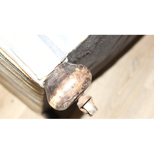 75 - In the manner of Howard & Sons, an antique deep seated armchair with multi-coloured stripey upholste... 