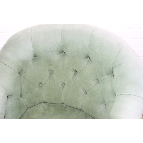 97 - An antique green upholstered tub chair with button backed upholstery, turned wooden legs and brass a... 