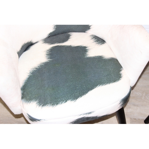 65 - A pair of retro style Ringo armchairs with black painted wooden legs, Friesian cow hide style uphols... 