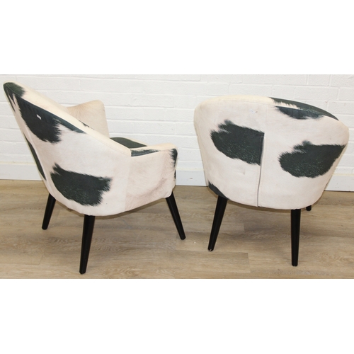 65 - A pair of retro style Ringo armchairs with black painted wooden legs, Friesian cow hide style uphols... 