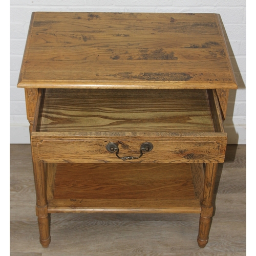 74 - A distressed oak bedside table with single drawer and brass handle, 65cm x 45cm x 75cm, one of two i... 
