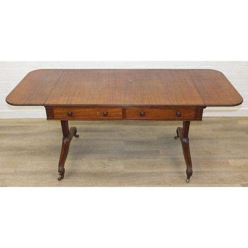 167 - A 19th century drop end mahogany sofa table with two drawers, scrolled legs with brass and ceramic c... 