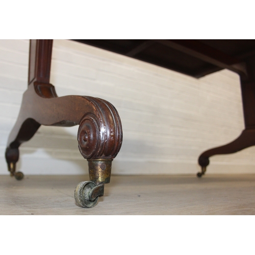 167 - A 19th century drop end mahogany sofa table with two drawers, scrolled legs with brass and ceramic c... 
