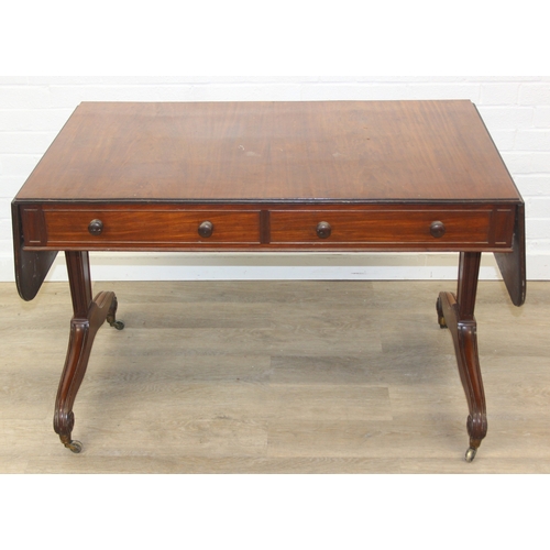 167 - A 19th century drop end mahogany sofa table with two drawers, scrolled legs with brass and ceramic c... 