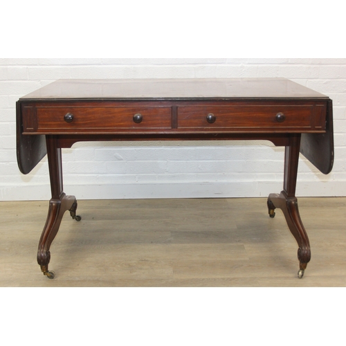 167 - A 19th century drop end mahogany sofa table with two drawers, scrolled legs with brass and ceramic c... 