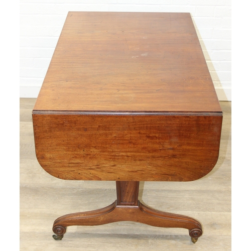 167 - A 19th century drop end mahogany sofa table with two drawers, scrolled legs with brass and ceramic c... 