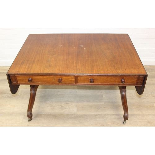 167 - A 19th century drop end mahogany sofa table with two drawers, scrolled legs with brass and ceramic c... 