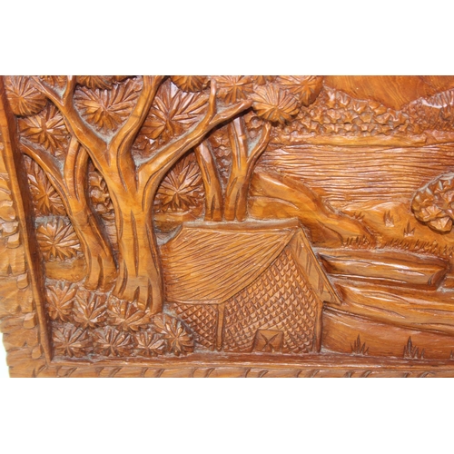 442 - An Asian carved relief hardwood panel depicting elephants and jungle, marked made in Thailand, 63cm ... 