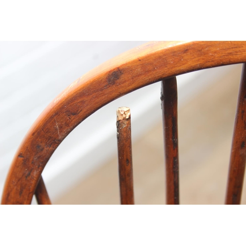 109 - An antique elm seated Thames Valley or Windsor farmhouse armchair with stick back and decorative spl... 