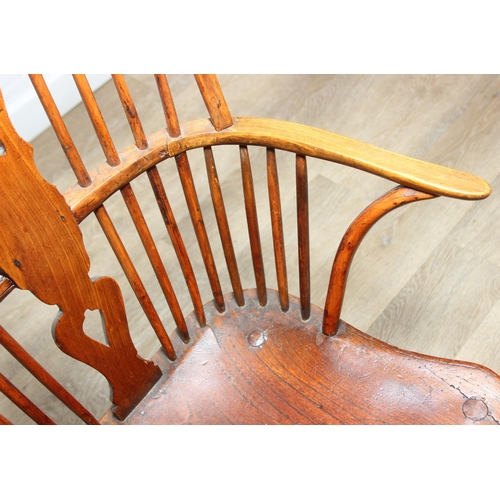 109 - An antique elm seated Thames Valley or Windsor farmhouse armchair with stick back and decorative spl... 