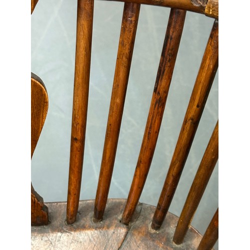 109 - An antique elm seated Thames Valley or Windsor farmhouse armchair with stick back and decorative spl... 