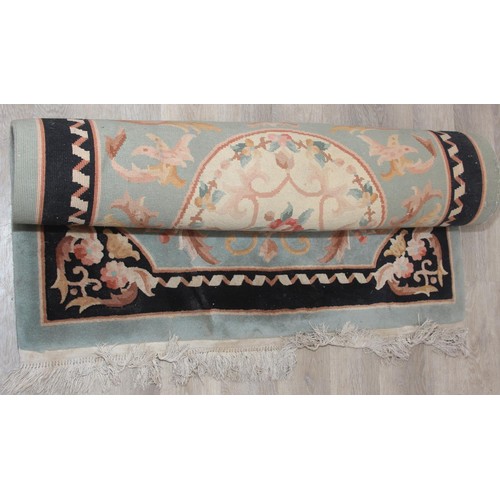 255 - A thick pile black and jade green ground rug with floral decoration, likely Chinese, 122cm x 186cm...