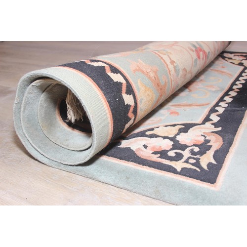255 - A thick pile black and jade green ground rug with floral decoration, likely Chinese, 122cm x 186cm...