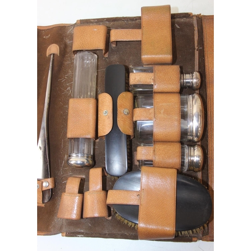 1006 - A leather cased gentleman's travelling vanity set, harlequin pieces but to include four silver toppe... 