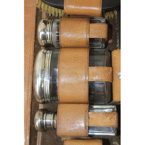 1006 - A leather cased gentleman's travelling vanity set, harlequin pieces but to include four silver toppe... 