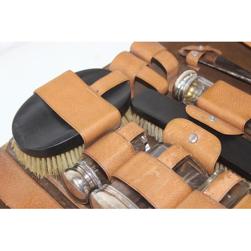 1006 - A leather cased gentleman's travelling vanity set, harlequin pieces but to include four silver toppe... 