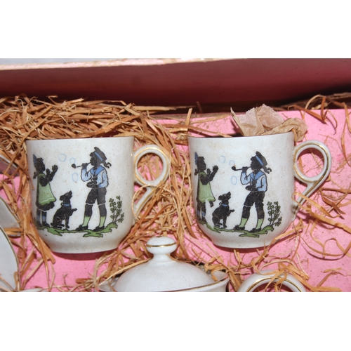 612 - A vintage boxed child's or dolls tea set decorated with scenes of children, with original straw fill... 