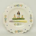 A Quimper pottery asparagus plate moulded with asparagus and painted with a musician and flowers, HB... 
