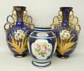 A pair of pottery twin handled vases of baluster form painted and gilded with daffodils and meadow f... 