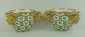 A pair of Sevres style porcelain cache pots, circa 1900, with triple ram's head handles, painted wit... 