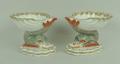 A pair of Berlin porcelain salts, late 19th century, the scallop shell bowls painted with birds, rai... 