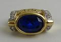 A gentleman's ring, marked 750 GD, with an oval cut sapphire coloured central stone, size N, 8.6g.