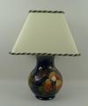 A Moorcroft pottery table lamp decorate in the 'Finches' pattern against a dark blue ground, impress... 