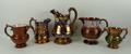 A group of copper lustre jugs, 19th century, comprising a jug of plain form, 12cm high, another moul... 