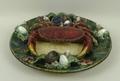 A Portuguese Palissy style dish, 20th century, modelled with a crab surrounded by shells and seaweed... 