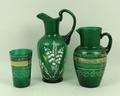 A green glass jug decorated in white and gilt with lily of the valley, 17cm, and a green glass jug a... 