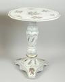 A Plaue porcelain occasional table of fluted, rococo form, painted with flowers, gilt heightened, 36... 