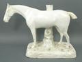 A stoneglazed figure of a horse, circa 1820, modelled standing against a tree stump, 34 by 13 by 23c... 