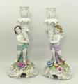 A pair of German porcelain figural candlesticks modelled with cherubs, raised on rococo scroll bases... 
