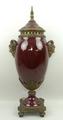 A porcelain and brass urn and integral cover, 20th century, red ground with twin satyr handles, leaf... 